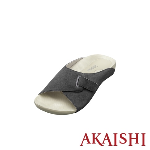 一只深灰色麂皮材質、可調節魔術貼帶的室內拖鞋，鞋底為米白色，鞋墊上有品牌標誌。