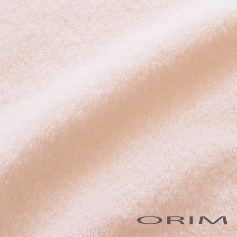 淺粉色毛巾，材質柔軟，表面呈現細緻的絨毛紋理，布料有自然垂墜的褶皺。