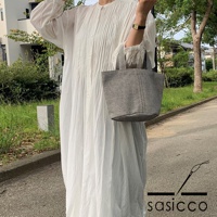 一位女士手持一個黑色和白色格紋圖案的圓底水桶包，包包由三河木綿刺子織製成。