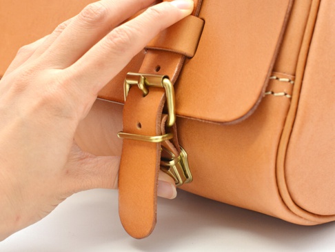 職人手作皮革屋瓦風三用側背包，採用天然棕色皮革製成，搭配復古黃銅色金屬扣環與縫線，展現精緻工藝。