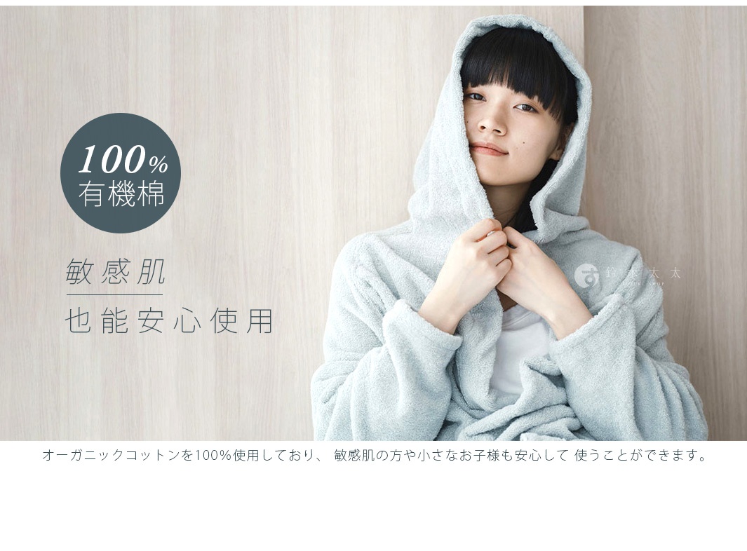 一位女性穿著淺藍色蓬鬆連帽浴袍，材質為有機棉，浴袍上有細緻的紋理。