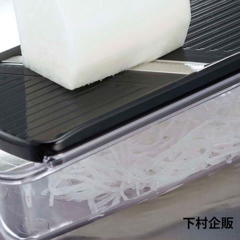 四合一刨絲器，黑色刨絲板，搭配透明儲物盒，內裝刨好的白蘿蔔絲。