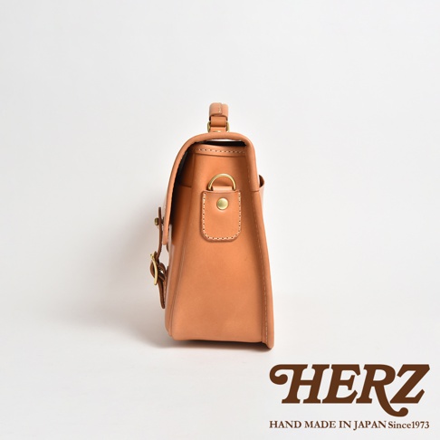 職人手作皮革商務休閒兩用單肩包 CW-10，展示淺棕色皮革材質。包包側面有提把、黃銅色金屬扣環和調整帶，設計簡潔。