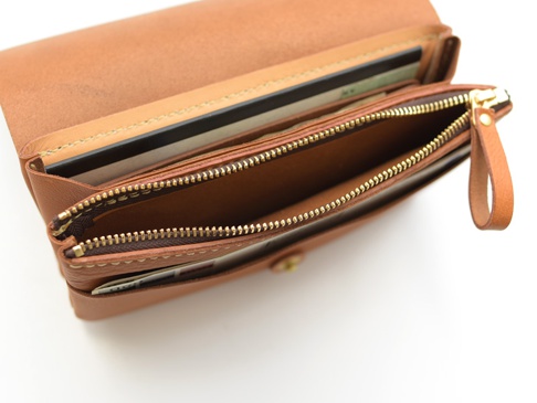 棕色皮革製長夾，內含多個隔層，可收納護照、機票和卡片，配有黃銅色拉鍊及皮革拉環。