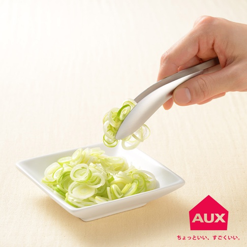 一只手正使用不鏽鋼材質的leye 不沾桌配料專用夾，夾起一小撮切好的蔥段，要放入裝有大量蔥段的白色方形盤中。
