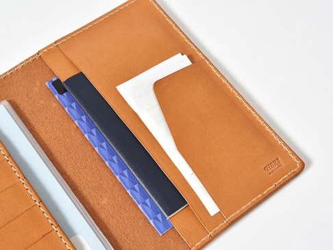 職人手作皮革多用途收納長夾 (KB-5)，採用鞣製過的棕色皮革製成，內部有多個隔層，可收納證件、票據和卡片。車縫線清晰，表面印有品牌標誌。