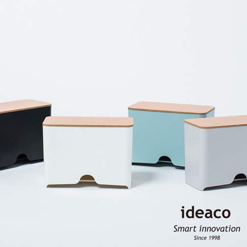 展示四個不同顏色的原木蓋口罩收納抽取盒，包括黑色、白色、淺藍色和灰色。每個收納盒都帶有淺木色的頂蓋，側面下方設有弧形開口。