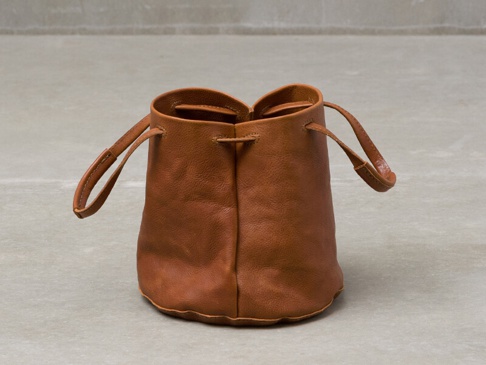 職人手作皮革Organ抽繩肩背手提托特包 (G-84) S，一個棕褐色皮革製成的圓筒形束口包，配有兩個短提把和一條抽繩，包身呈現自然的皮革紋理。