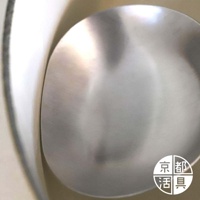 不鏽鋼萬用料理大勺的勺面，呈現拉絲紋理的銀灰色，勺緣邊緣有細微的光澤。