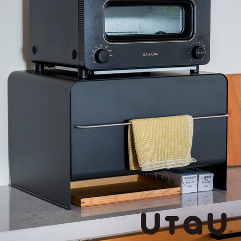 UtaU 品牌抽屜式收納櫃，上方擺放黑色烤箱，櫃門掛著黃色擦手巾，下方擺放木質托盤和兩卷保鮮膜。