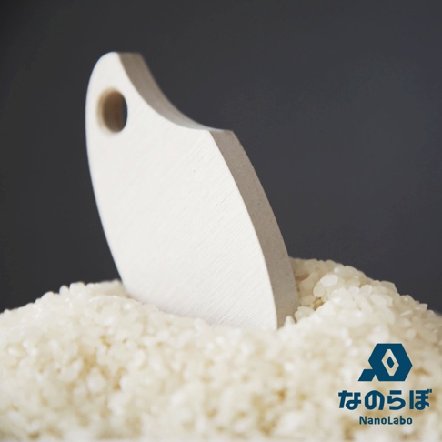 由珪藻土製成的白色米勺，置於裝滿稻米的碗中，背景為深灰色。右下角有NANOLABO品牌標誌及日文與英文名稱。