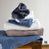 一疊 Lisse 蓬鬆柔感有機棉毛巾，包括深灰色、白色、藍色和棕色。毛巾質地柔軟，堆疊展示。