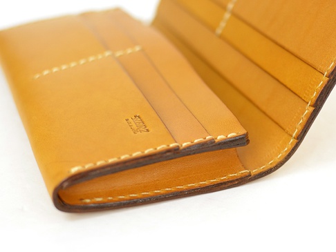 淺棕色皮革長夾，內部有多個卡片夾層，縫線清晰。皮革表面有「HERZ MADE IN JAPAN」壓印。