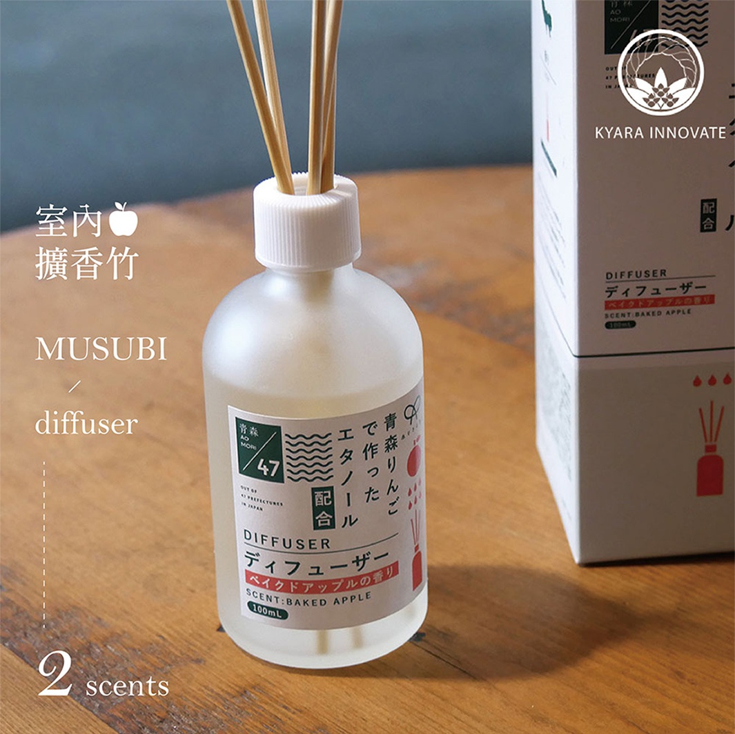 室內擴香竹 MUSUBI diffuser，搭配著附有蘋果圖案的標籤，瓶身旁還有同款香氛盒，上面印有日文和英文說明，包含DIFFUSER、SCENT: BAKED APPLE及100ML等字樣。