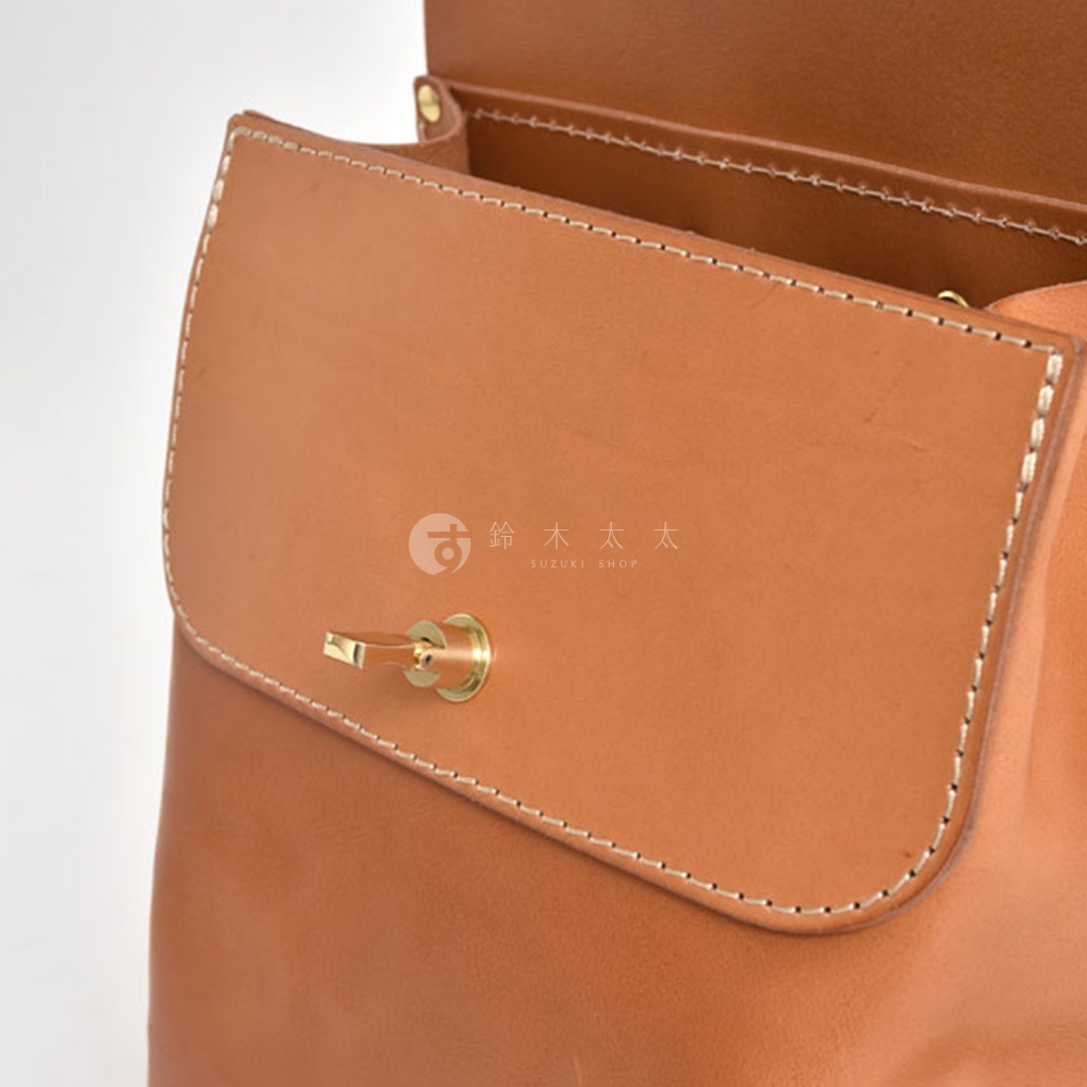 職人手作皮革翻蓋迷你後背包 R-34，採用淺棕色牛皮材質，縫線清晰。包包正面有金屬旋轉鎖扣，翻蓋設計，結構簡潔。