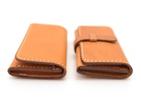 兩個淺棕色皮革名片夾，一個有皮革壓扣束帶，均以白色縫線手工製作。