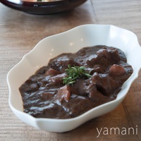 淡青白釉美濃燒輪花長盤盛有燉牛肉，牛肉塊浸在濃郁的深棕色醬汁中，點綴著迷迭香。