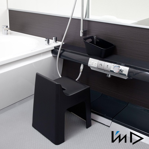 黑色一體成型塑膠椅凳，設計簡約，底部有簍空結構，椅面帶有弧度，適合搭配衛浴空間使用。