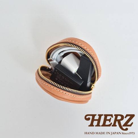 職人手作皮革三角飯糰造型小物收納包，淺棕色，可裝載充電器、電池和線材，採用拉鍊開合。
