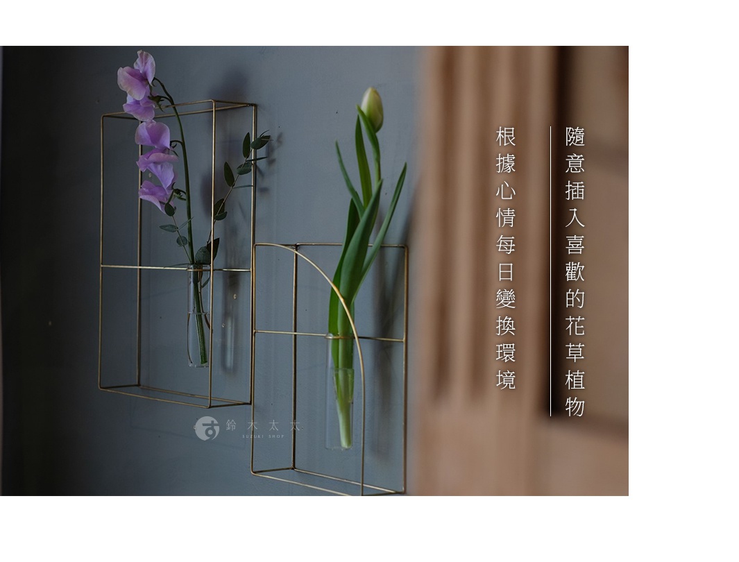 黃銅金屬線條構成的書架造型掛擺兩用花器，一側插有紫色花朵，另一側插有綠色花苞，簡約現代。
