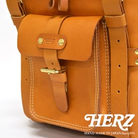 職人手作皮革大型三用旅行後背包，展示部分為焦糖棕色皮革，帶有明顯的縫線細節、皮帶扣和品牌標誌。