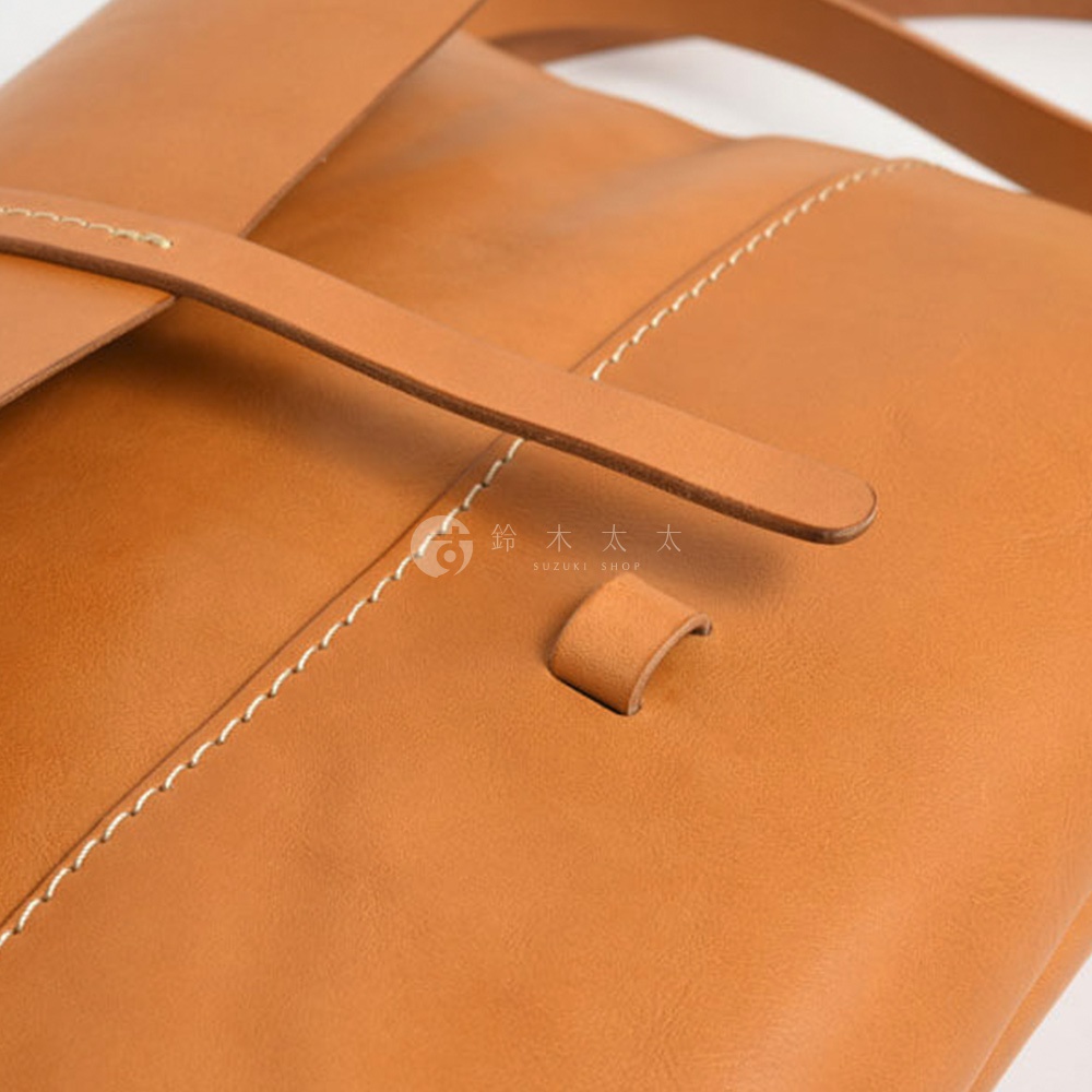 HERZ 職人手作皮革細扣帶馬鞍包 CK-3 的特寫，展現焦糖色皮革紋理、縫線細節和品牌 logo