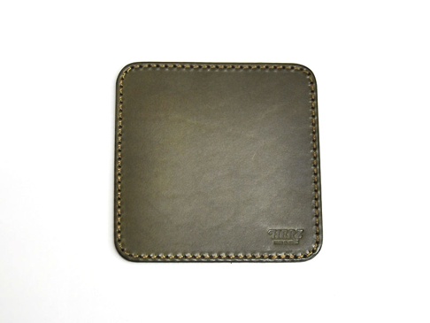 職人手作皮革印章墊板，方形，深橄欖綠色，邊緣縫線為淺褐色，右下角有壓印的品牌標誌。