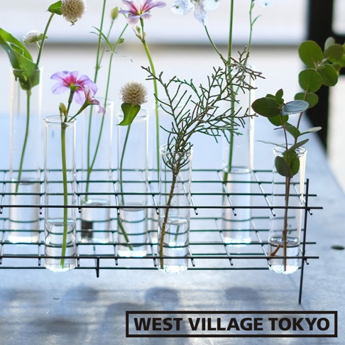 多格一輪玻璃花器 S，黑色金屬支架，內含六個透明玻璃管，每管插有不同種類的花草，包括粉色、白色小花及綠葉枝條。