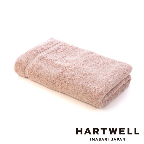 一條粉色、輕盈、觸感柔軟的今治毛巾，材質為純棉，表面有細緻的毛圈紋理，邊緣有條紋裝飾。