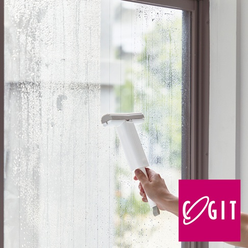 手持白色推拉式海綿刷，正在清潔佈滿水珠的玻璃窗。海綿刷頭為灰色，帶有可伸縮的設計。