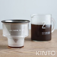 透明玻璃濾杯組，內含金屬濾網，印有英文文字；搭配裝有深色咖啡的透明玻璃分享壺，壺身印有白色數字「2」，整體置於木質桌面。