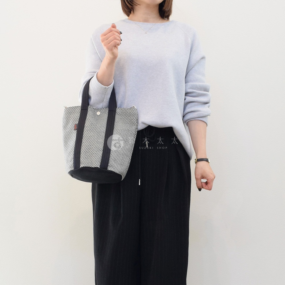 三河木綿刺子織兩用水桶包，織紋為黑白格紋，搭配黑色提把與底部，簡約實用。