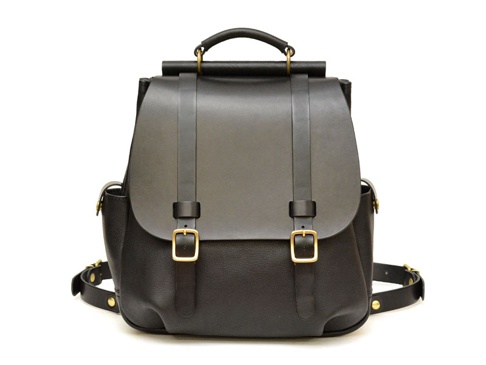 黑色皮革後背包，具備屋瓦式翻蓋設計，兩條皮帶扣環，頂部有提把，側面有小口袋，並有可調節的肩帶。