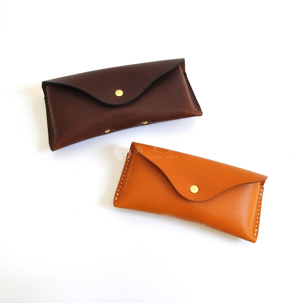 兩個皮革眼鏡收納盒，一個深棕色，一個淺棕色，均配有金色按扣。