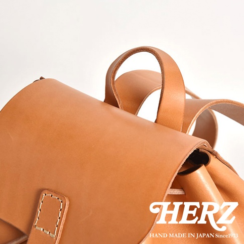 職人手作皮革經典後背包R-4，採用天然皮革材質，顏色為淺棕色。特寫展示了背包的頂部結構、提把以及縫線細節，展現其精緻工藝。