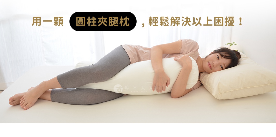 一名女子側臥，雙腿夾著一個白色圓柱形夾腿枕，枕套為純白色，枕頭填充飽滿，提供支撐。