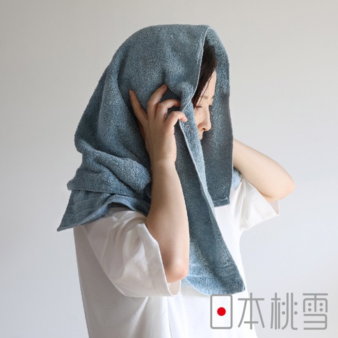 一名女性將一條淺藍色、觸感柔軟的毛巾包裹在頭上，毛巾邊緣帶有明顯的縫線。