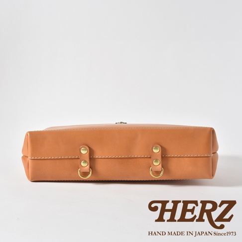 職人手作皮革軟式杜勒斯三用背包，採用鞣製皮革材質，呈現自然棕色調。包款正面有兩組黃銅色金屬扣環與D型環，搭配雙縫線設計，風格簡約。