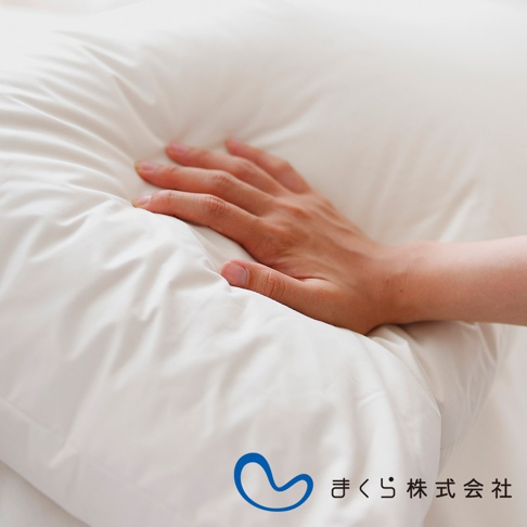 手輕壓在白色柔軟的羽毛枕上，枕頭呈現蓬鬆的紋理。