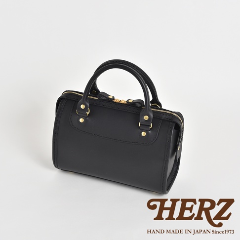 黑色皮革迷你波士頓包，設有金色拉鍊和五金配件，以及兩條手提帶，採用職人手作工藝製成。