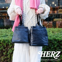 兩款黑色皮革單柄手提包，其中一款較小，兩款皆有束口設計，由穿著粗針織毛衣和粉色圍巾的人士展示。