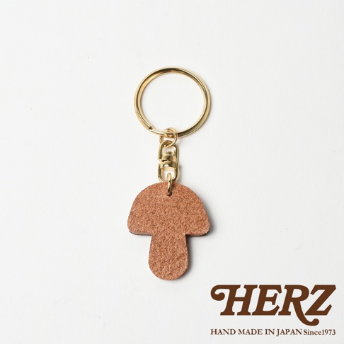 棕色皮革香菇造型鑰匙圈，搭配金色金屬鑰匙環與掛鉤，呈現簡約可愛的設計。