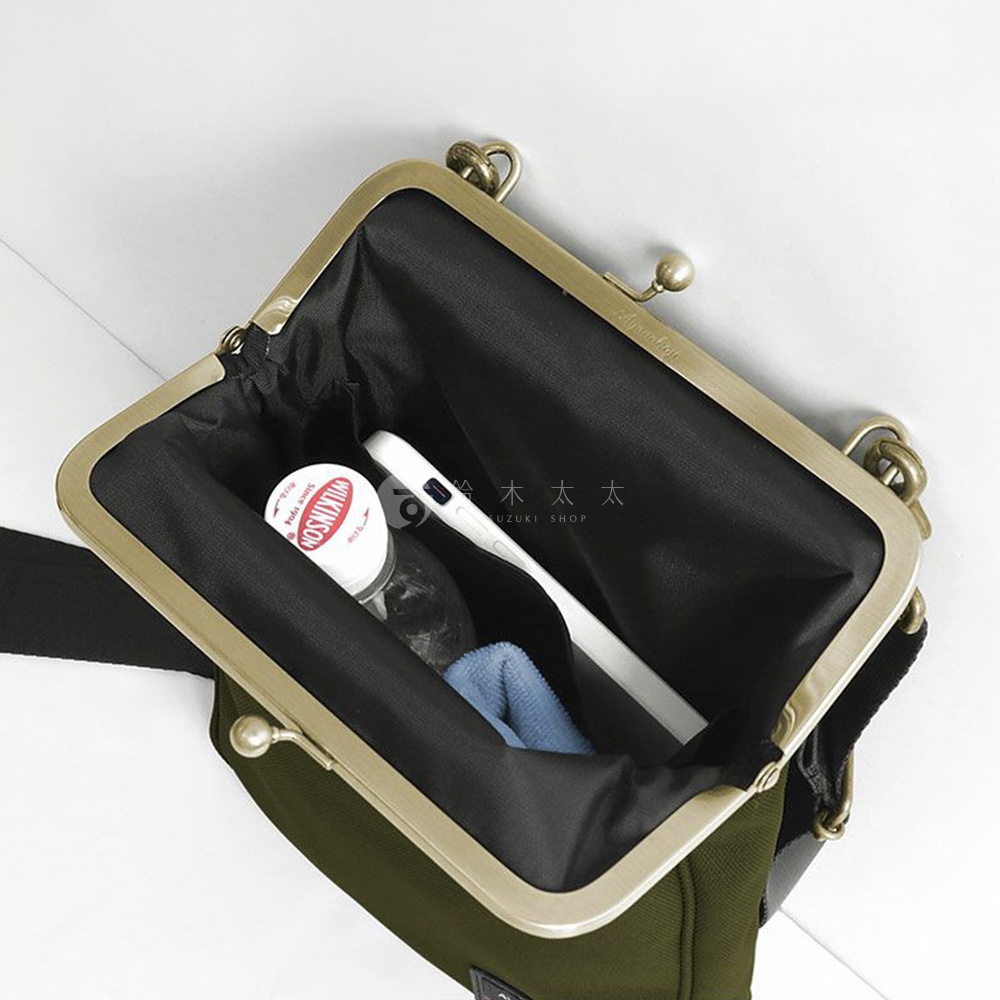 一個裝有化妝品和手機的綠色口金包，內襯為黑色。