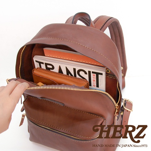 職人手作皮革休閒風後背包 R-93，深棕色皮革，內部可見雜誌與皮夾，風格簡約實用。