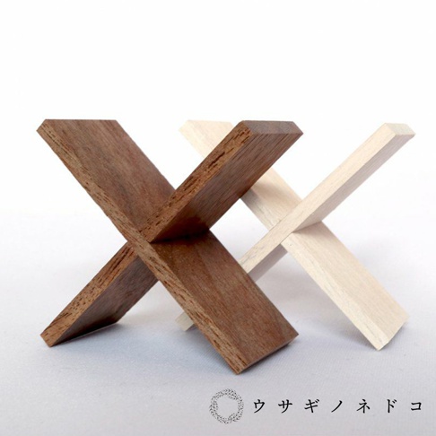 兩個顏色（深棕色和淺色）的木質立方塊置物架，以「X」型結構交叉擺放。