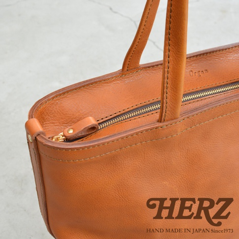 職人手作皮革Organ肩背拉鍊托特包，棕褐色皮革，拉鍊開合，HERZ品牌標誌。