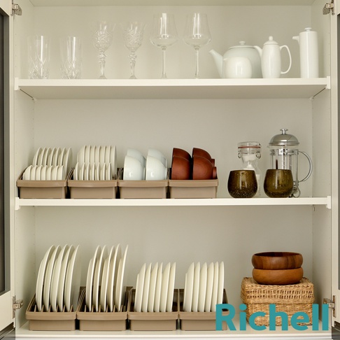 櫥櫃的層架上擺放著各式餐具，包含玻璃杯、酒杯、茶壺、咖啡機、碗盤及木碗等，部分餐具收納於褐色的餐盤架中。