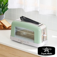 淺綠色搭配銀色不鏽鋼邊框的烤麵包機，配有黑色夾子，機身側面有透明玻璃視窗，底部有旋鈕和按鈕。