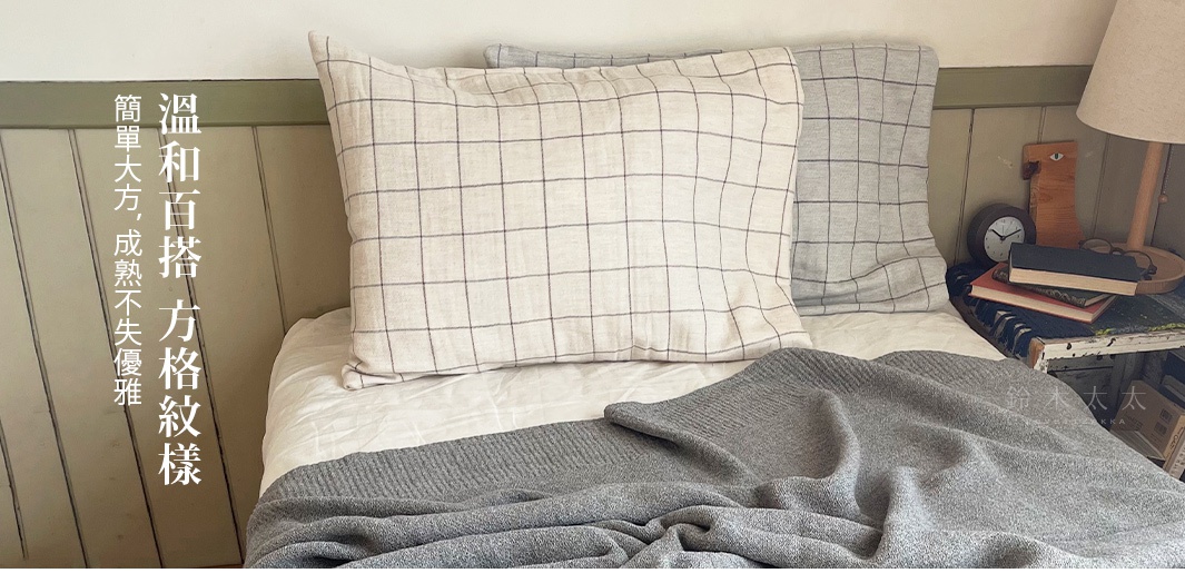 草木染格紋有機棉枕套，米白色枕套搭配深色格紋，另一枕套為淺灰色格紋，材質柔軟，呈現溫和簡約的風格。
