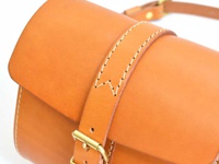 職人手作皮革皮扣單肩包，選用天然棕色皮革製作，帶有精緻的縫線細節，並配有黃銅金屬皮扣，風格簡約實用。